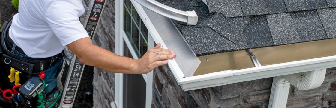 LeafFilter installation technician installing the product on a corner of a house with stone siding