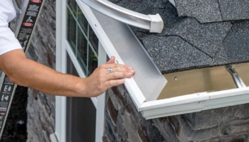 LeafFilter installation technician installing the product on a corner of a house with stone siding