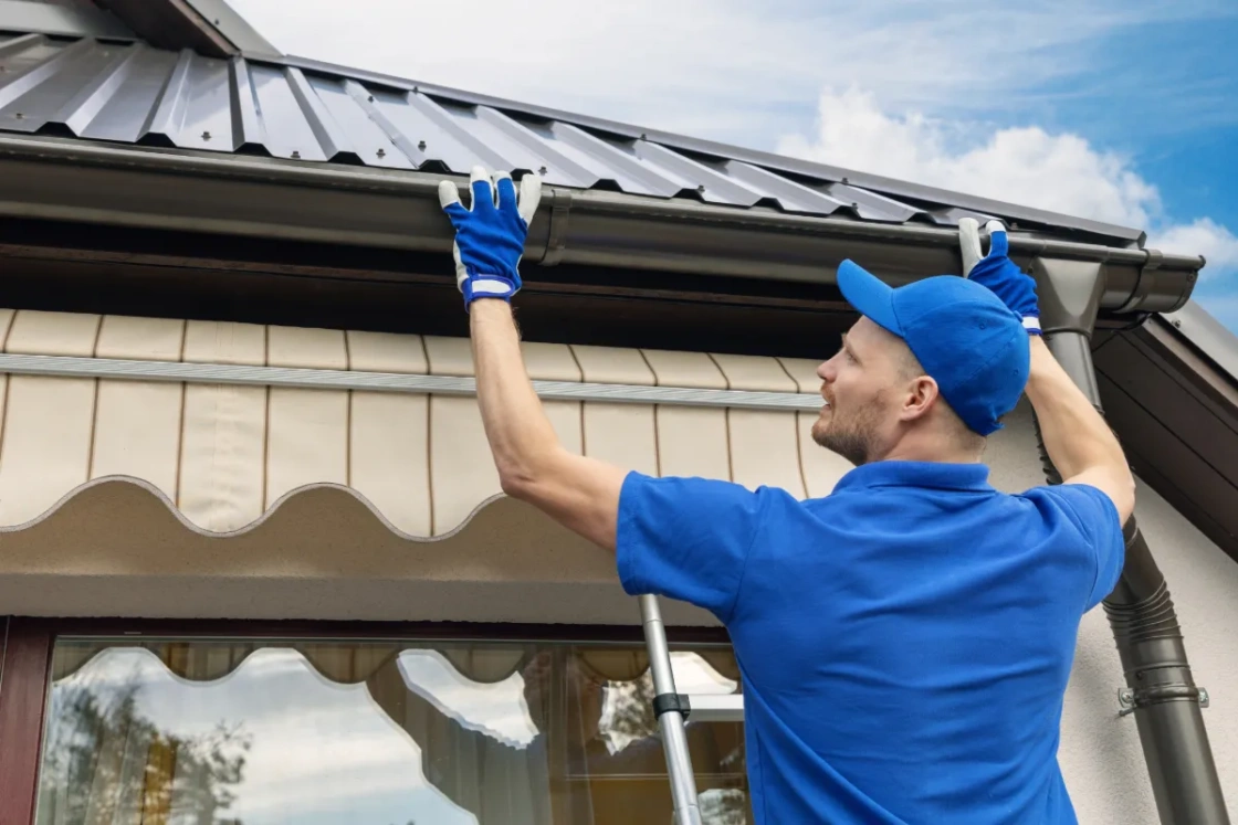 Man installing gutters on house